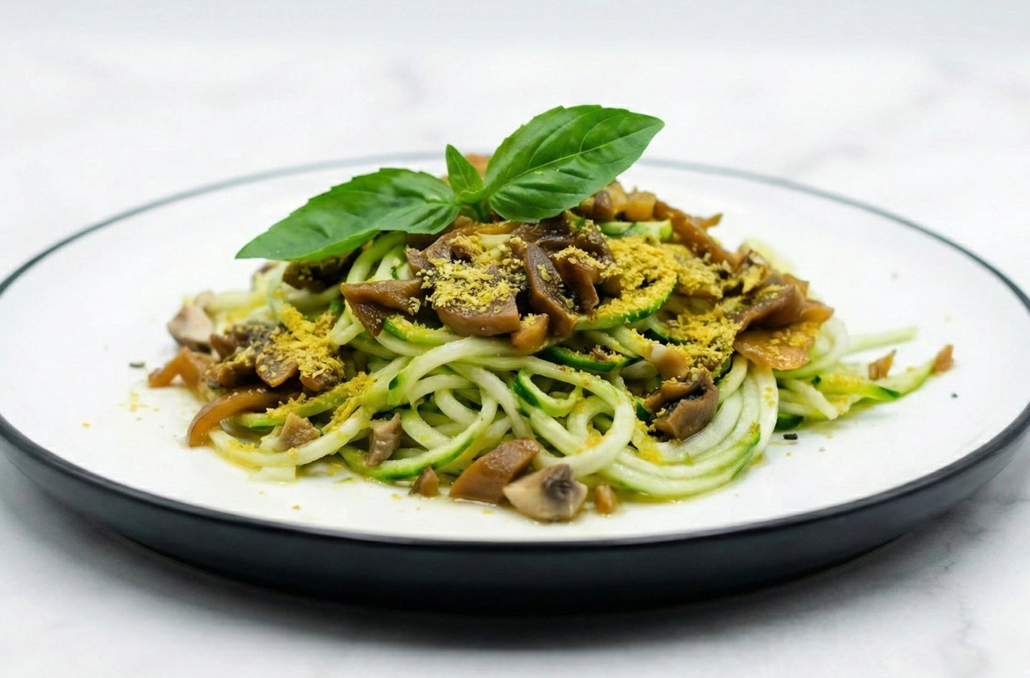 Zucchini noodles with mushrooms and herbs on a white plate