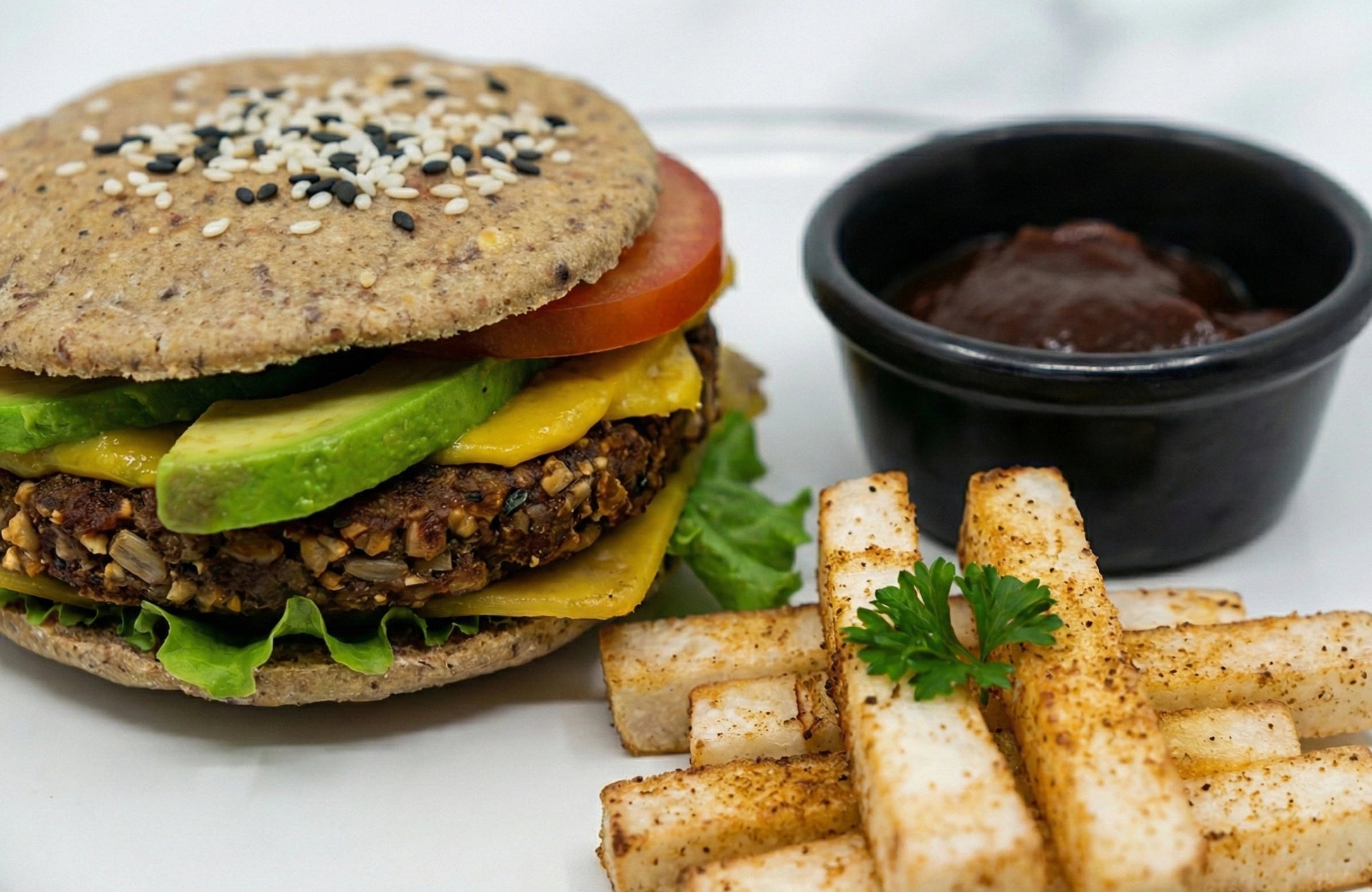 Vegan burger with fries and a side of ketchup on a white plate